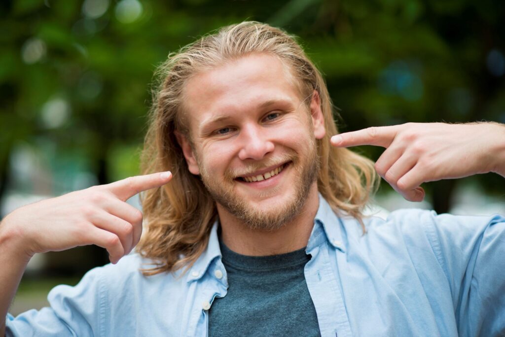 Uomo sorridente che indica il proprio viso a rappresentare la felicità e la qualità di vita in Finlandia. Viaggi in Finlandia Monica Alberghini.