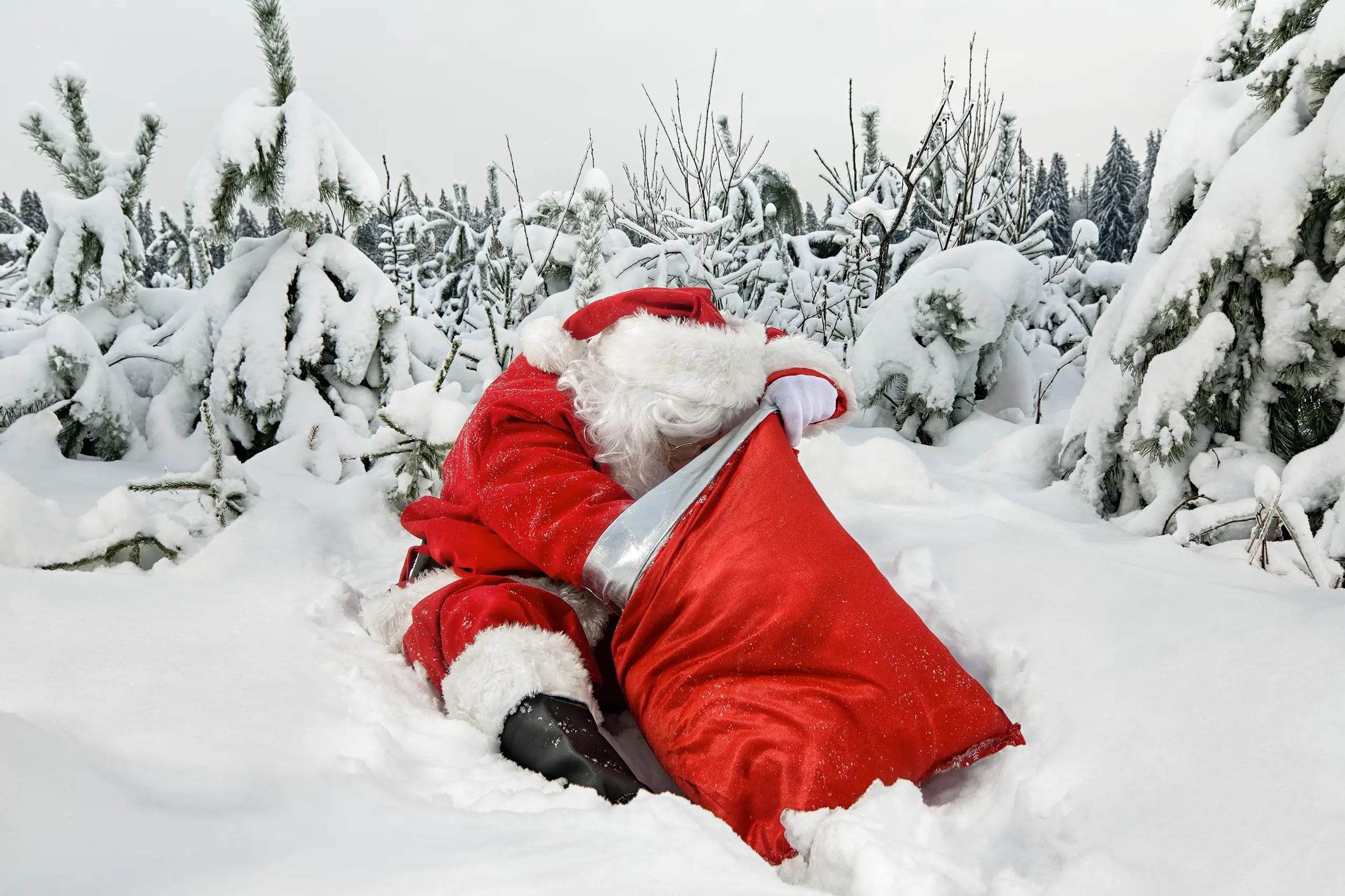 Babbo Natale con il suo sacco rosso seduto sulla neve in una foresta innevata nella Lapponia finlandese, Monica Alberghini viaggi su misura.