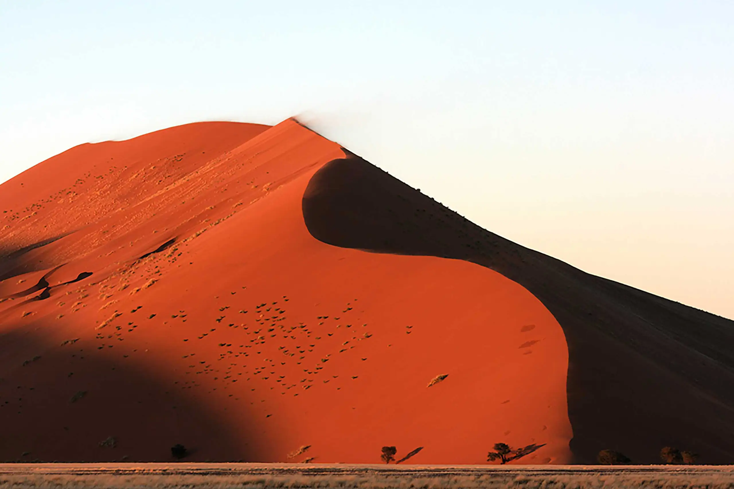 Duna di sabbia rossa illuminata dalla luce del sole al tramonto nel deserto della Namibia, viaggio avventura proposto da Monica Alberghini.