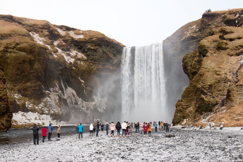 Turisti in visita alla cascata Skógafoss in Islanda durante l’inverno